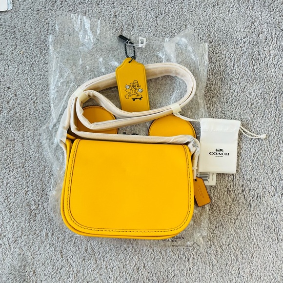 Coach Handbags - New authentic Coach Disney, Crossbody with Mickey Mouse ears, in banana color.